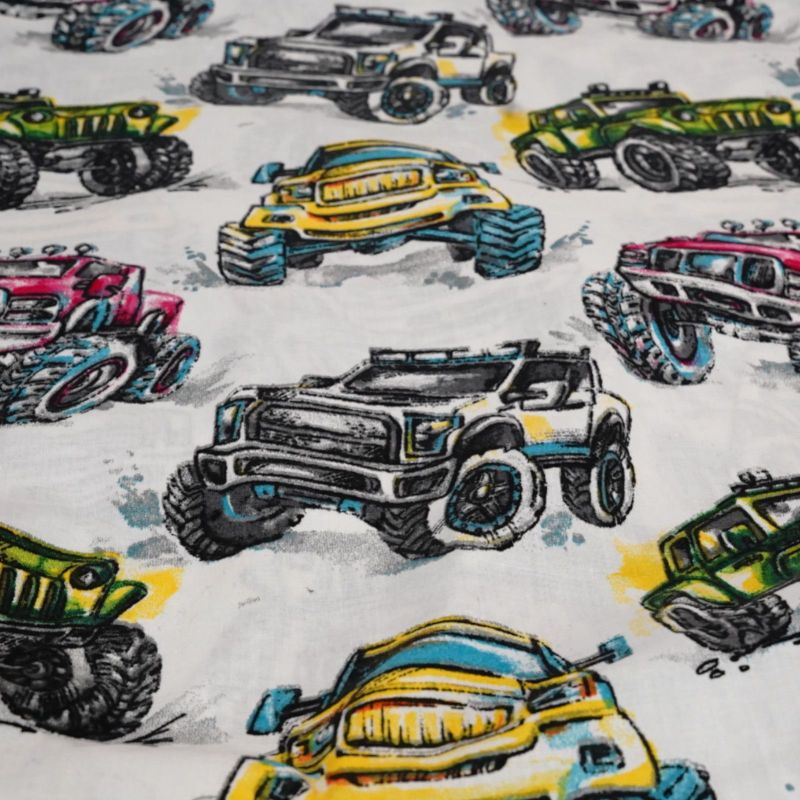 Zbliżenie na bawełnianą tkaninę z kolorowym wzorem terenowych monster trucków.